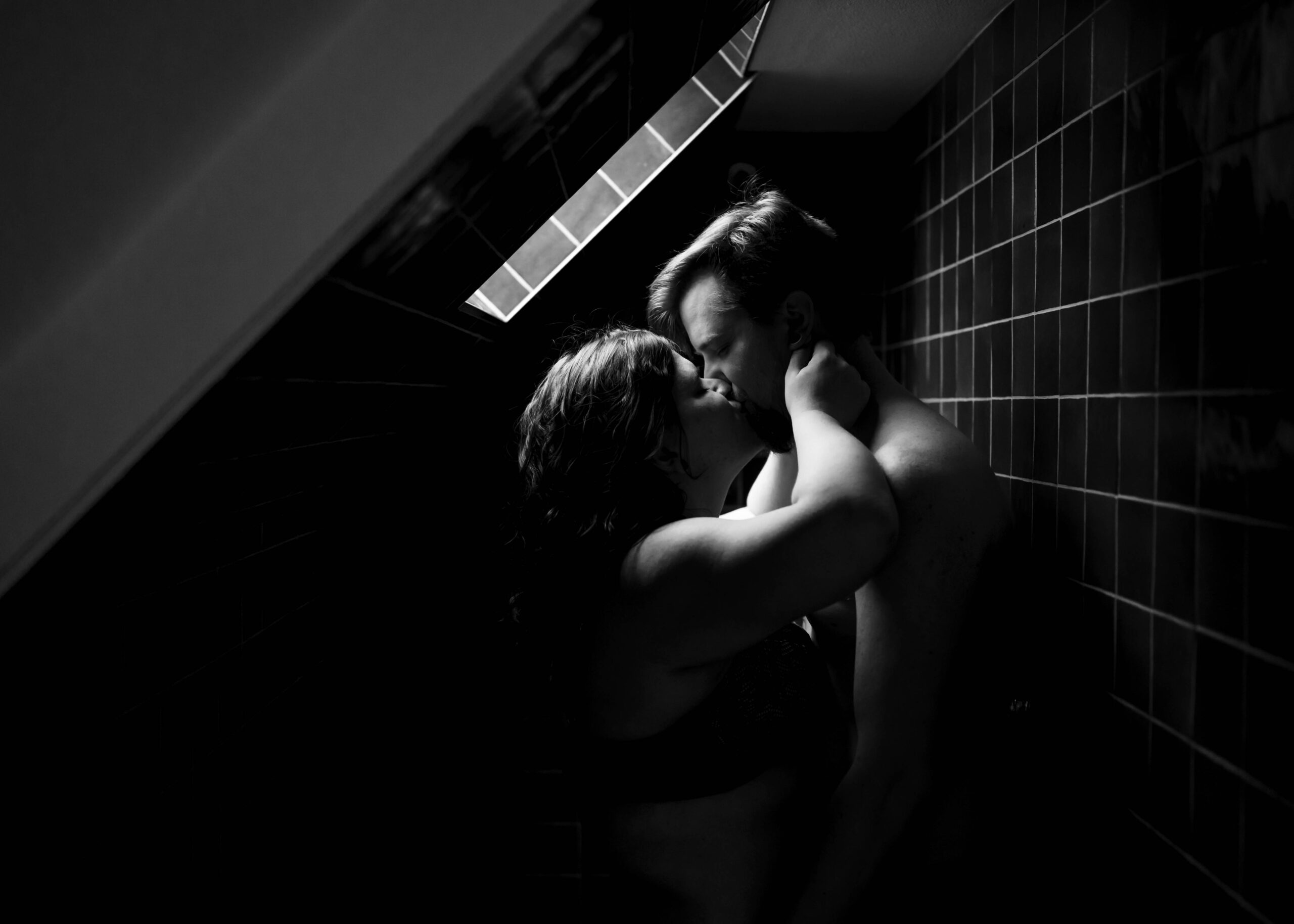 Couple kissing in shower in black and white photo during couples boudoir session