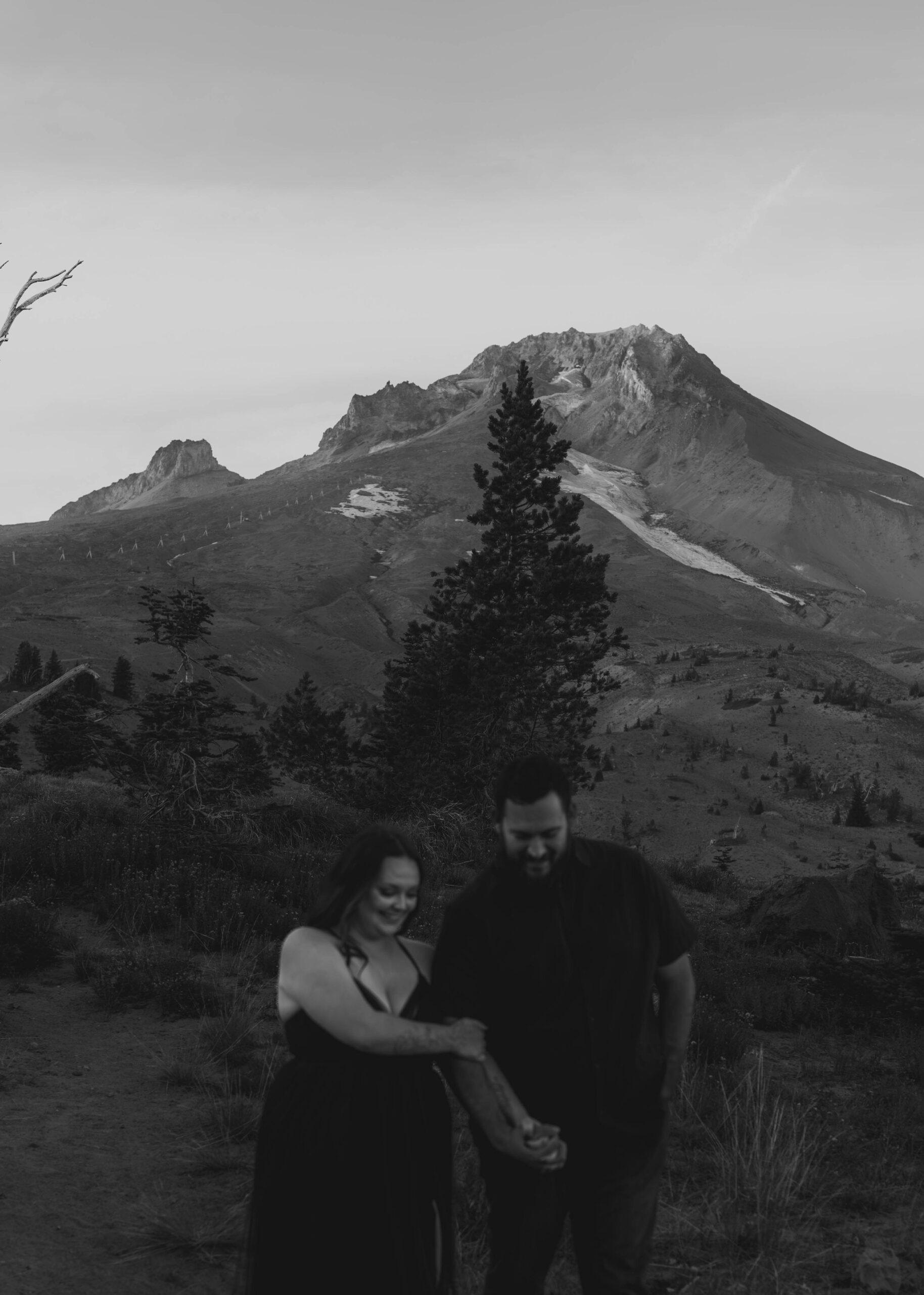 couple holding hands walking together with big mountain behind them black and white photo