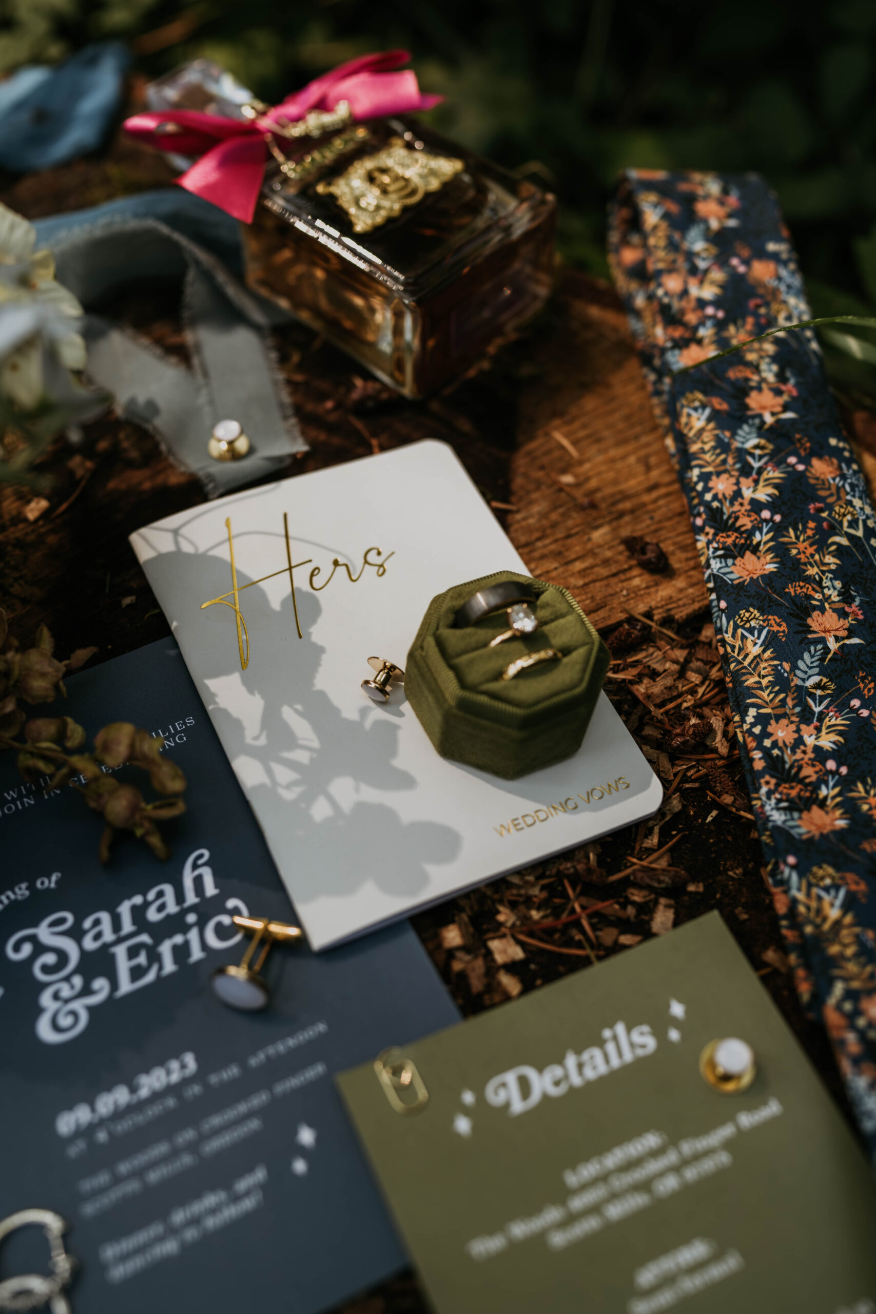 wedding flat lay details of rings, invites, floral, vow books, perfume, etc