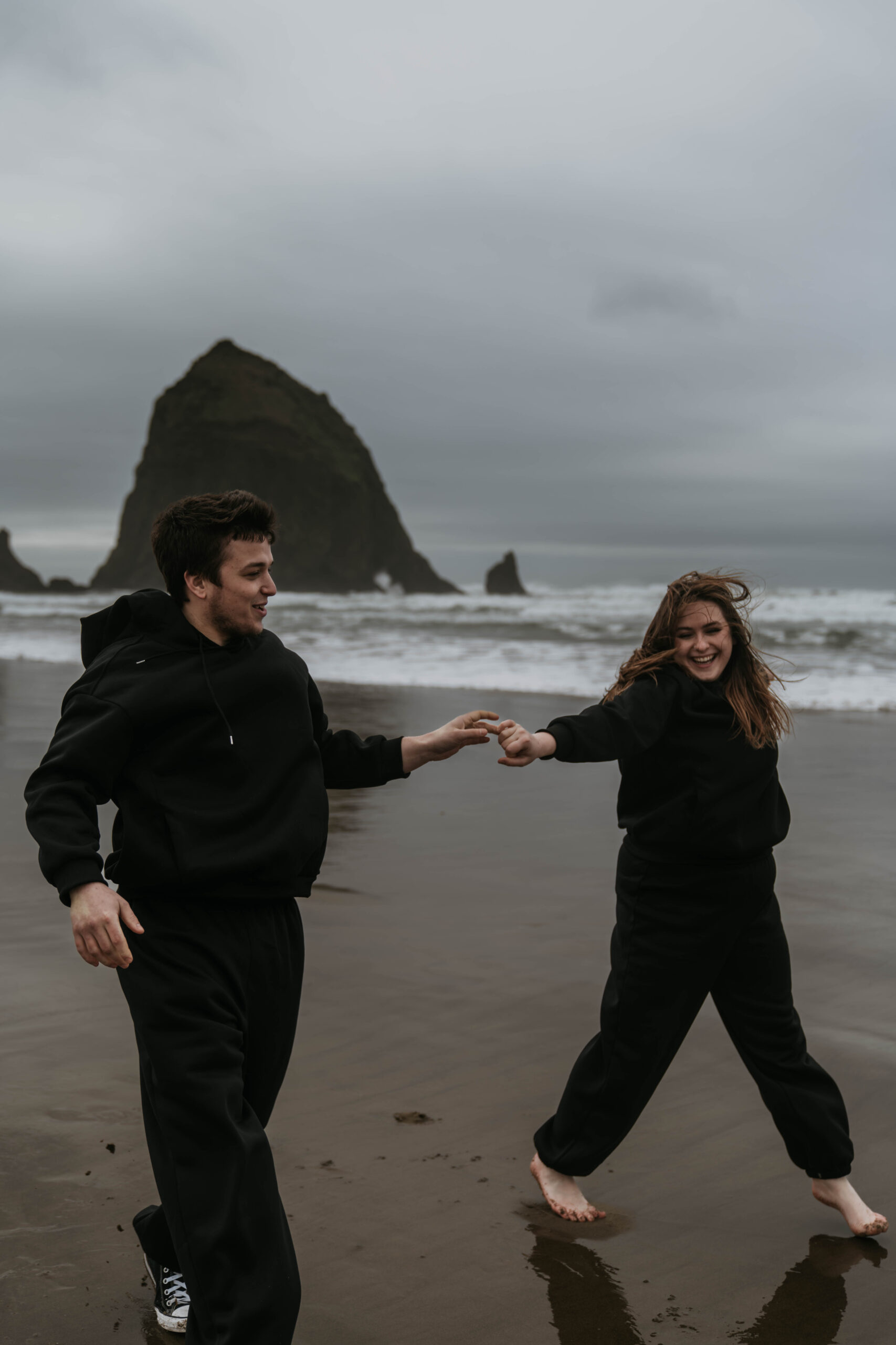 couple holding hands running on the beach laughing
