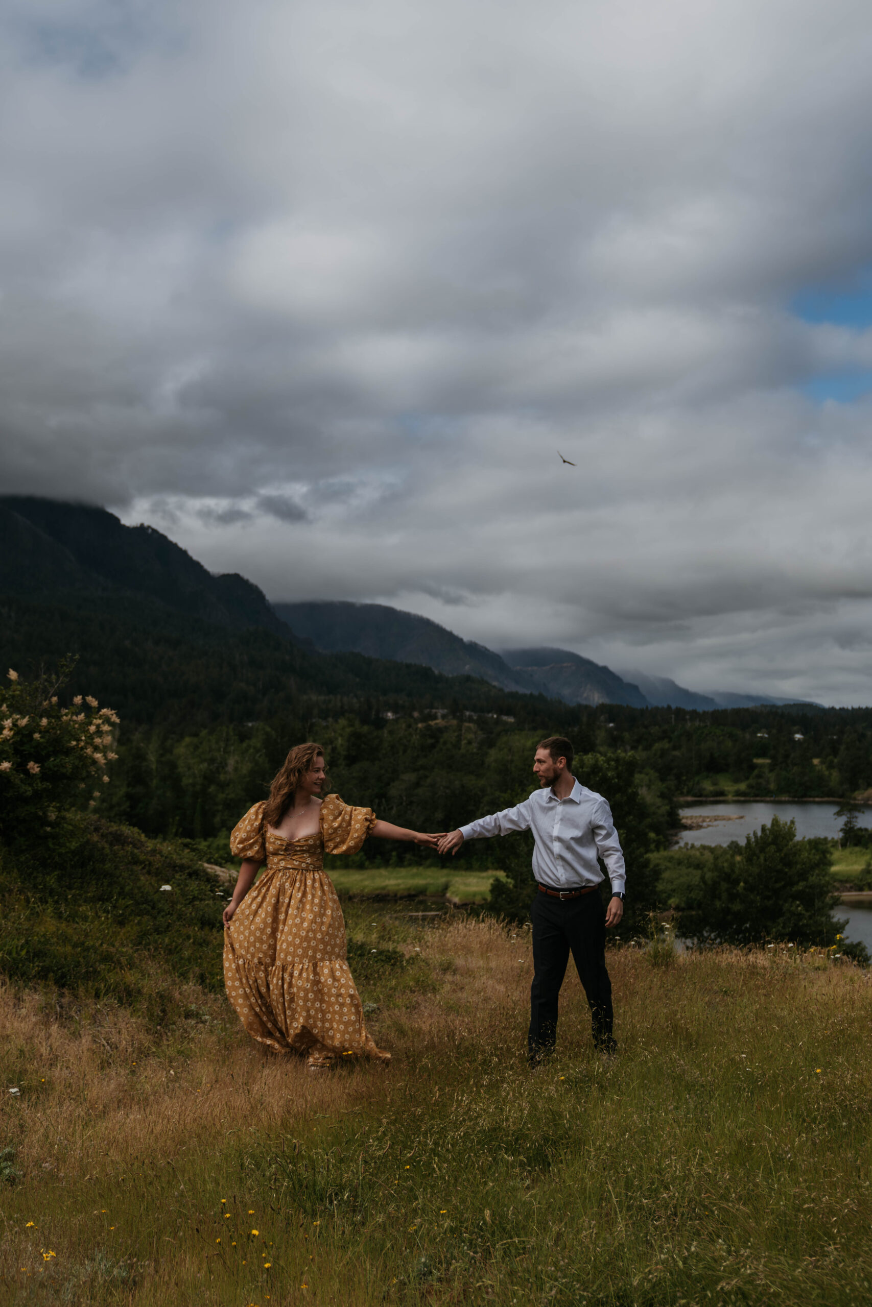 couple walking spaced out from each other with mountain backdrop on cloudy day