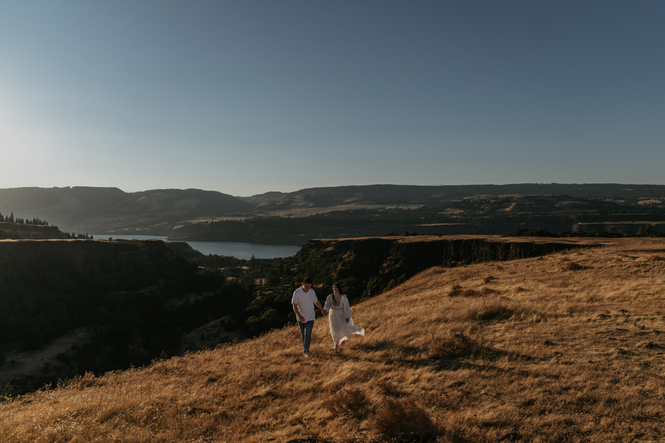 couple in a distance walking together with sunset backdrop of views