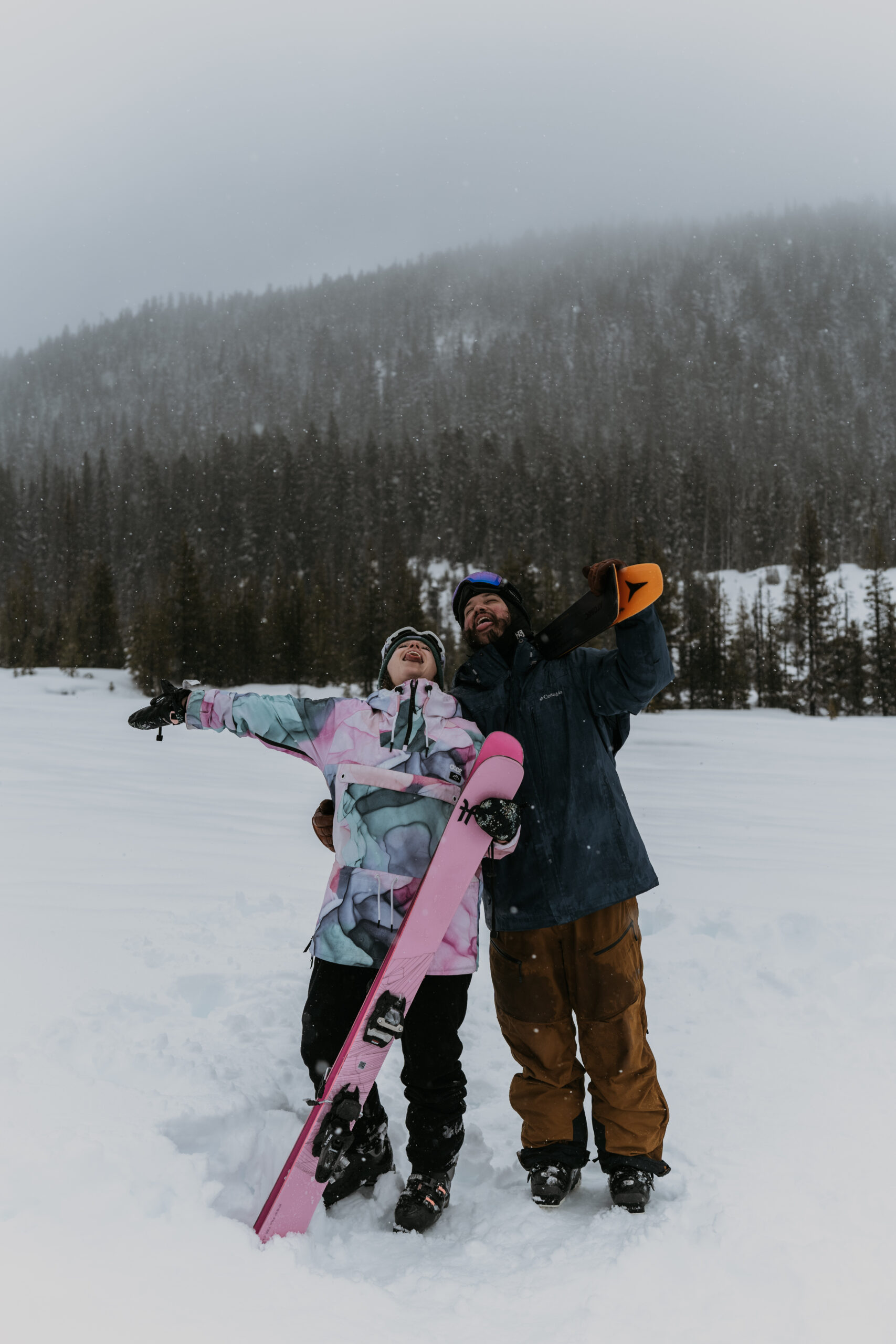 couple standing in snow in ski gear catching snowflakes in their mouth