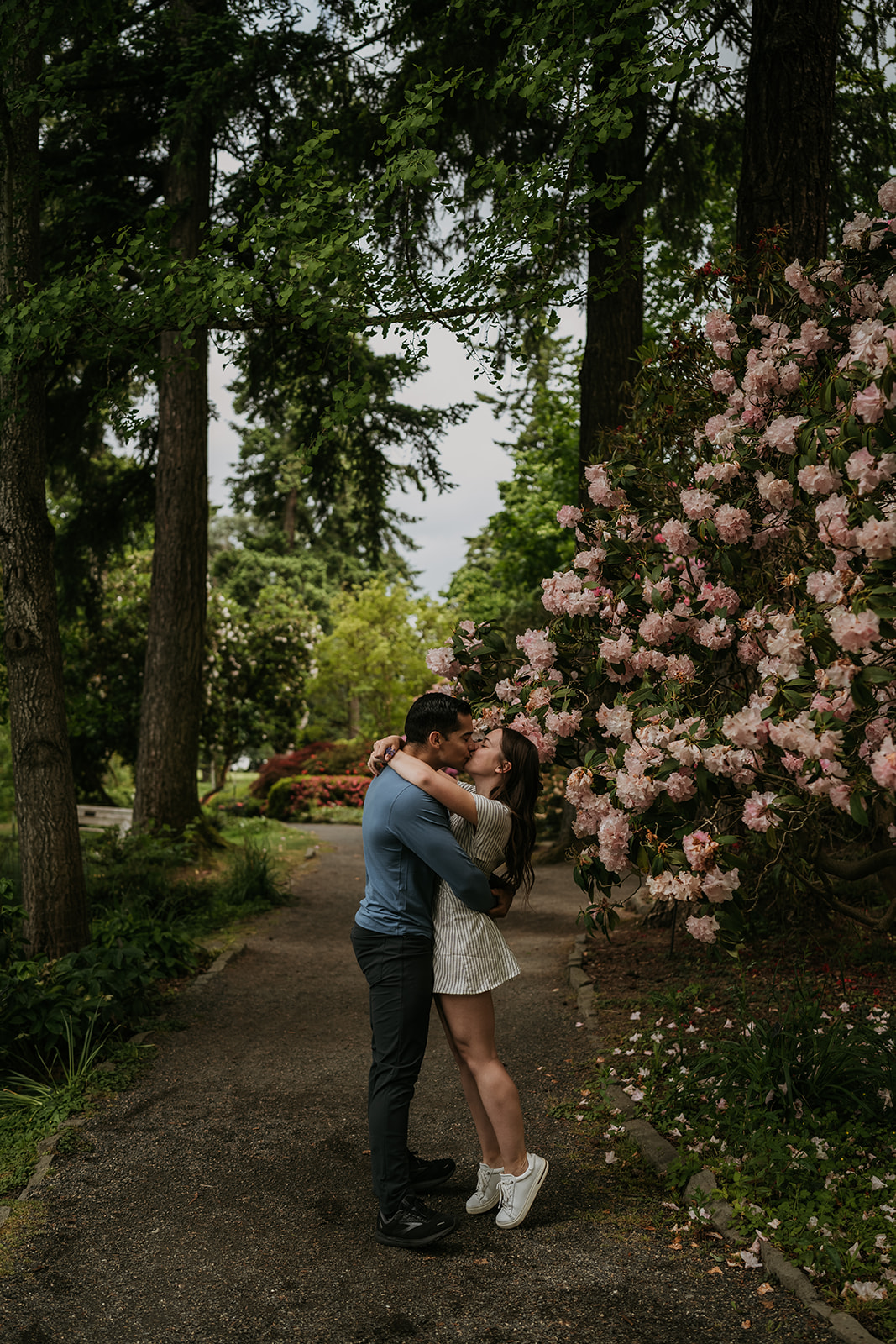 couple kissing on path with wildflowers and trees surrounding them