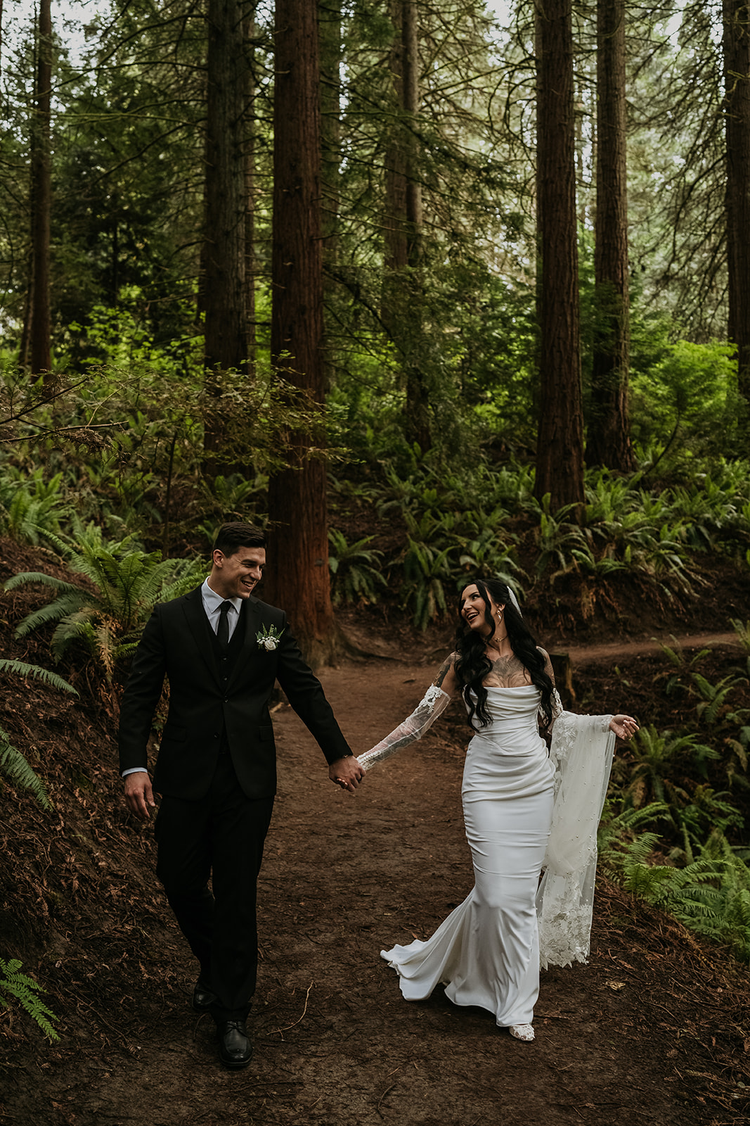 bride and groom holding hands walking on trail in forest