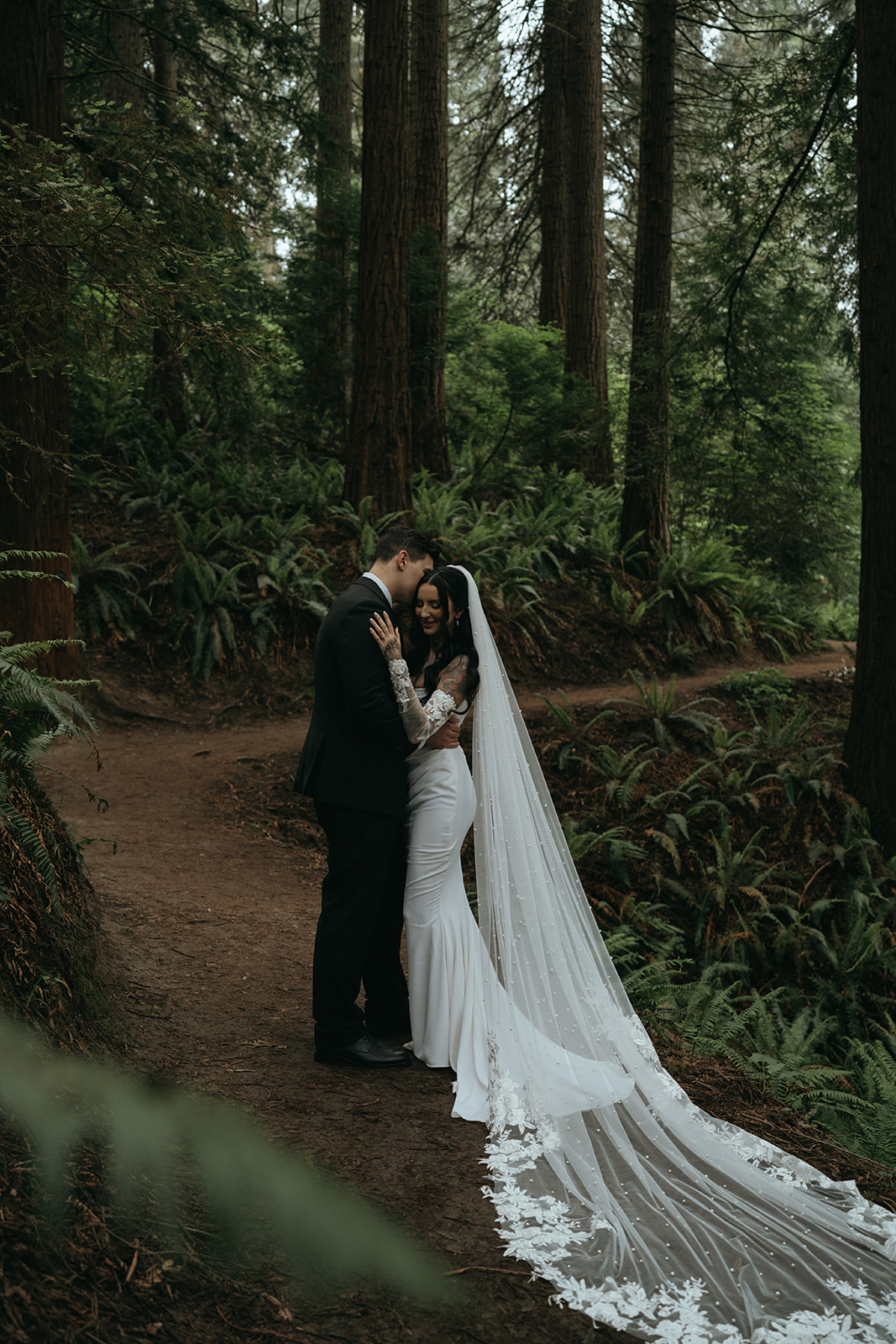 bride and groom holding each other close in a dark forest in a tight hug
