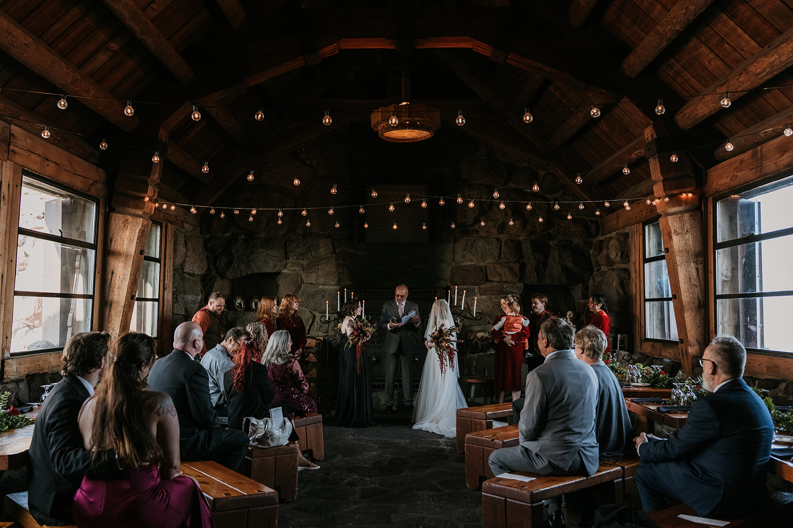 two brides at alter getting married in dark venue with skulls, lights, and warm tones