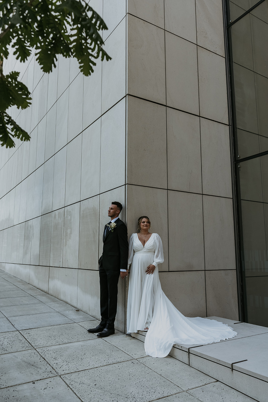 pregnant bride holding grooms hand standing in front of courthouse