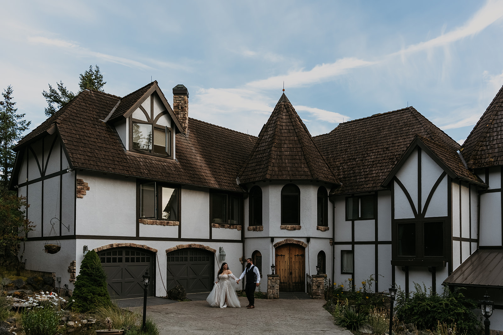bride and groom walking together in front of castle-like home