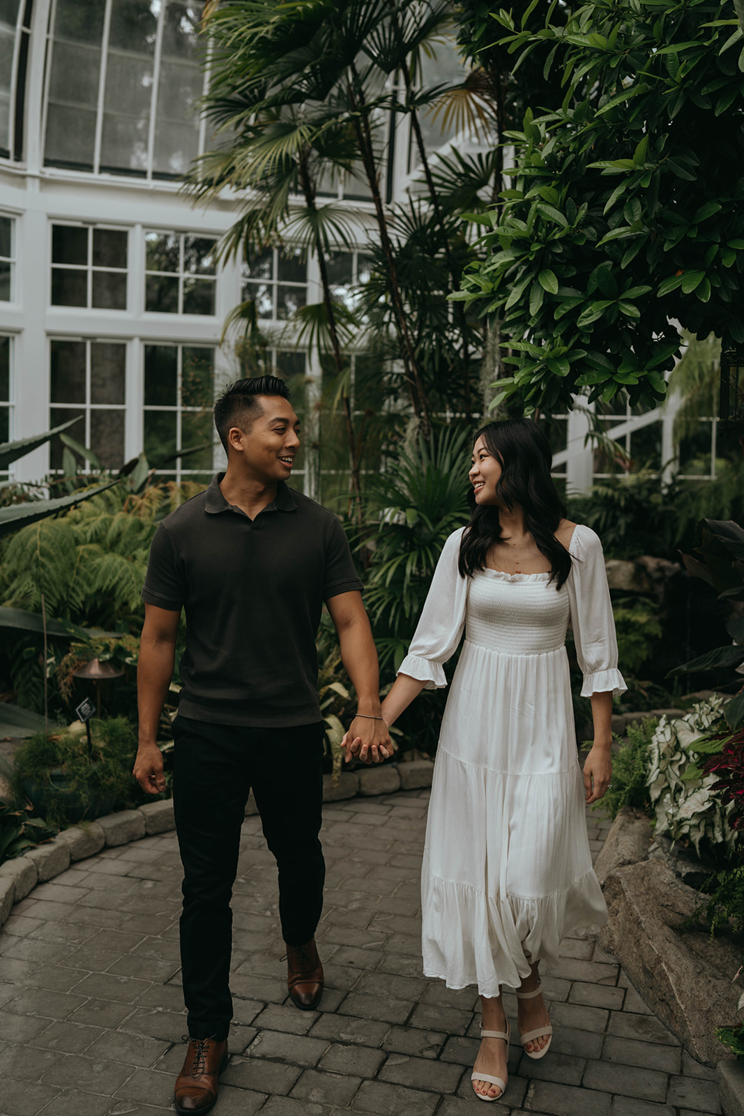 man and women walking holding hands in greenhouse surrounded by plants