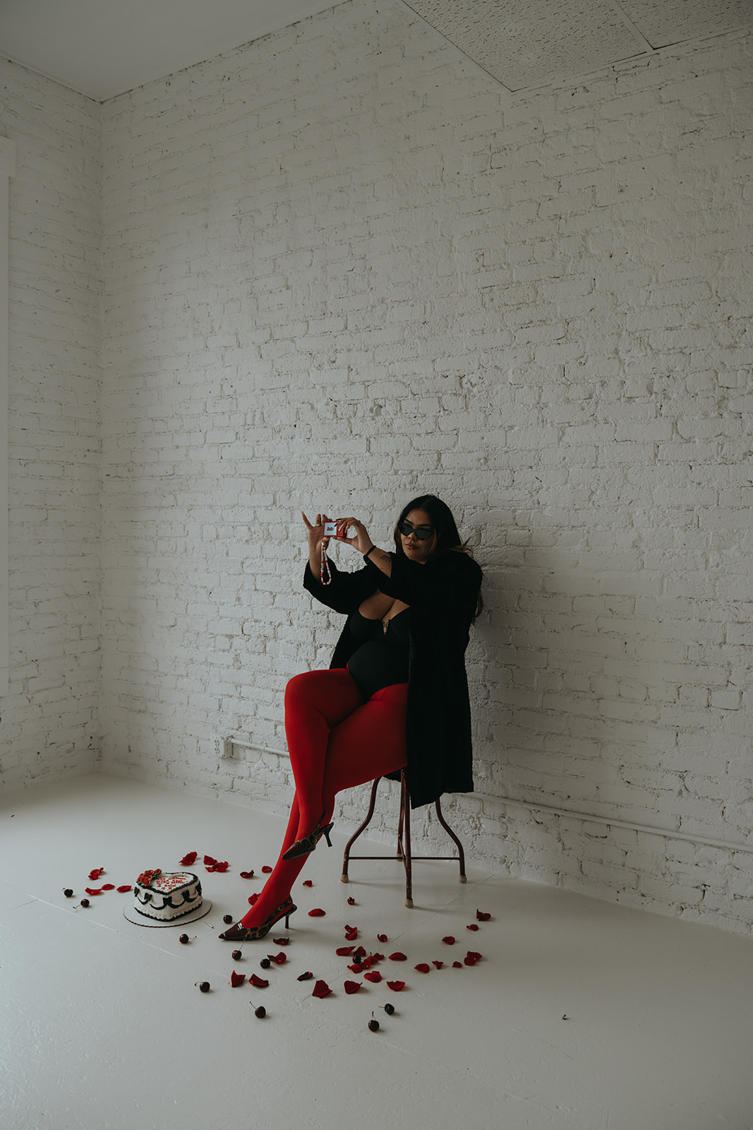 women in red tights sitting on stool taking photo of self in lingerie with cake and roses and candles