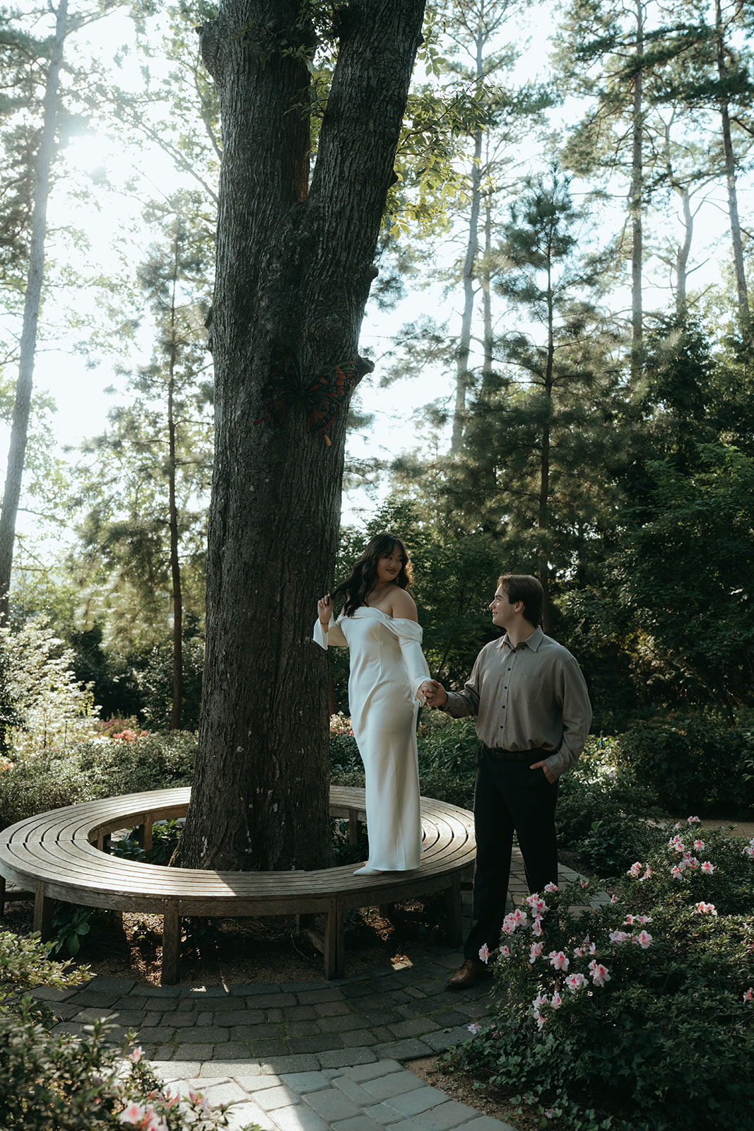 girl in white dress holding hand with man in forested area walking together with glowing sunlight