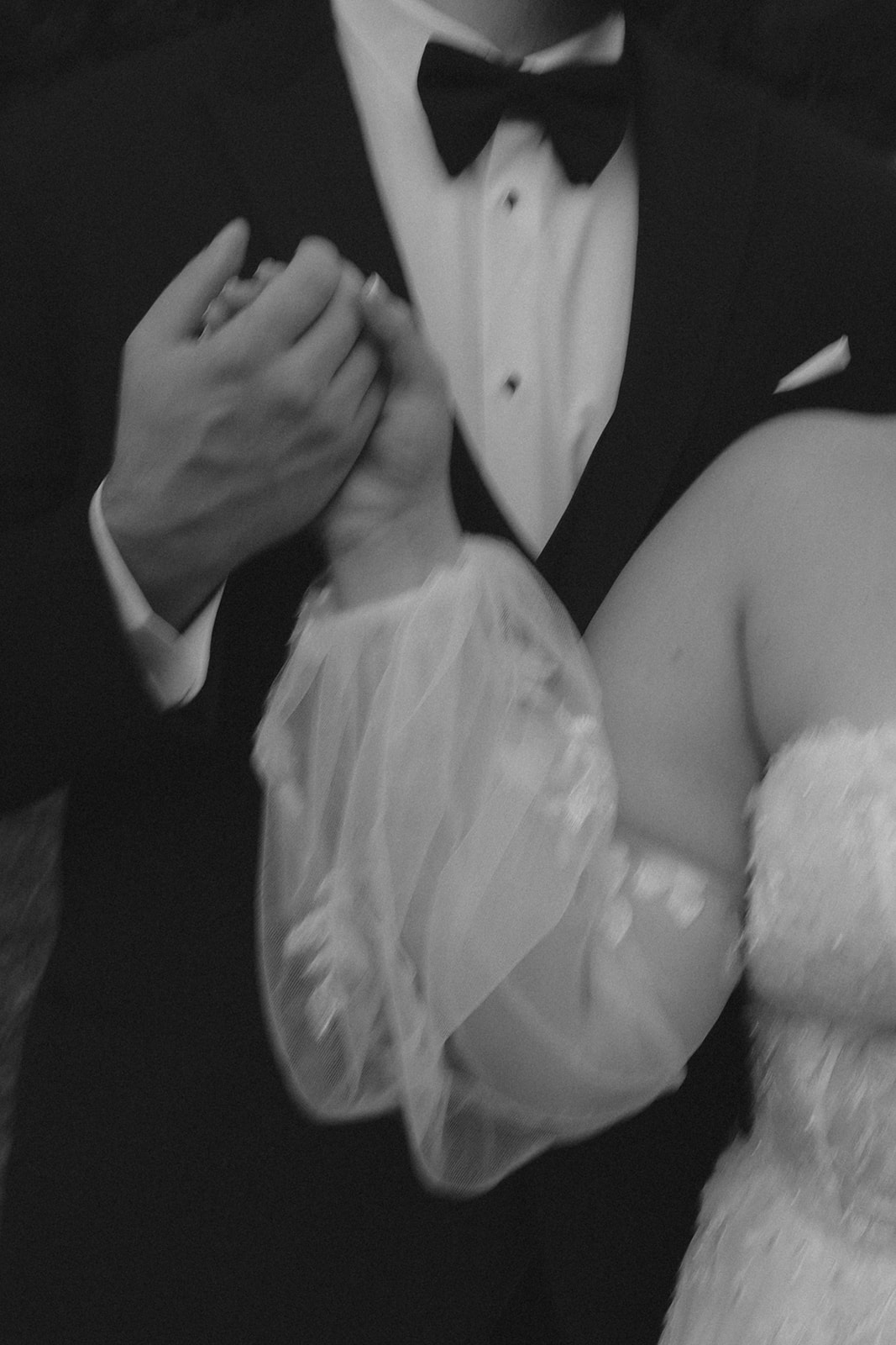 black and white of bride and groom holding hands